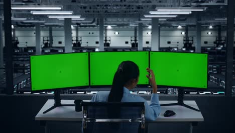 back view of asian woman having headache while working with mock up multiple computer monitor in data center