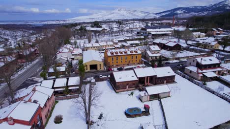 low cinematic aerial over the snow-covered buildings and streets of spains pradera in the midst of winter