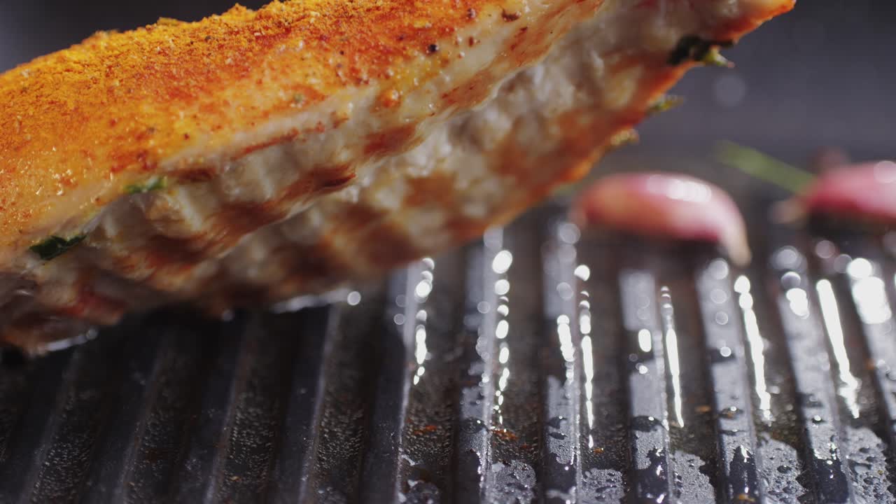 Cooking raw chicken meat in yellow turmeric spice with garlic and greens on grill close-up. Preparing raw food for cooking. Grilled chicken, duck, turkey kebab with vegetables.