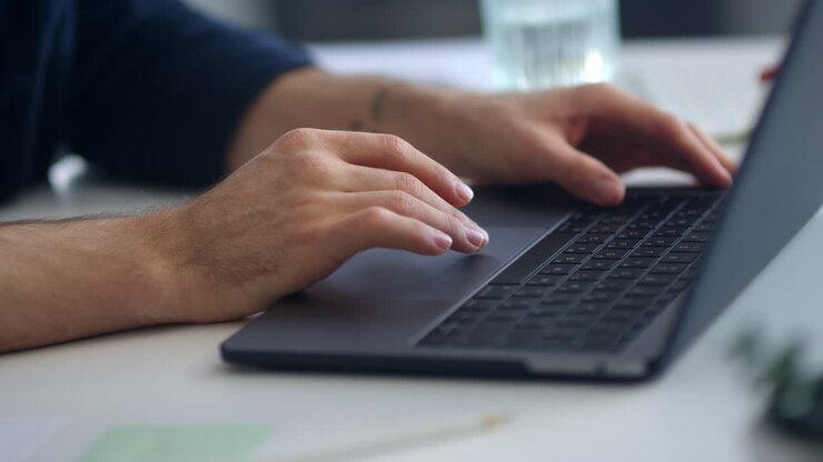 Close-up view of man hands surfing internet on computer touchpad