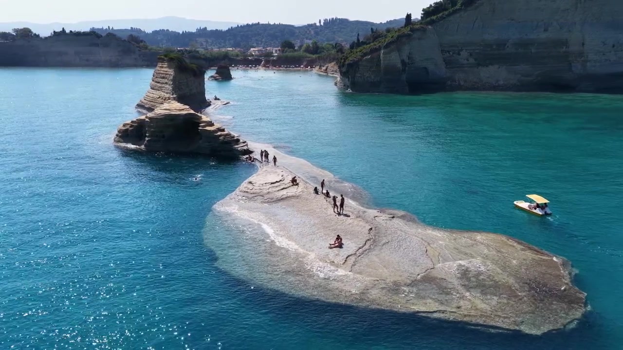 Aerial drone view of tourists on Apotripiti beach rock formation in turquoise Ionian sea, Sidari, Corfu, Greece, day