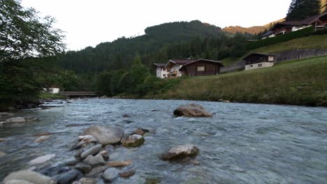 idyllic flowing river next to a group of holidays houses in a mountain range from a low perspective