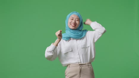 아시아 여성이 녹색 스크린 배경 스튜디오에 서서 미소 짓고 춤을 춘다