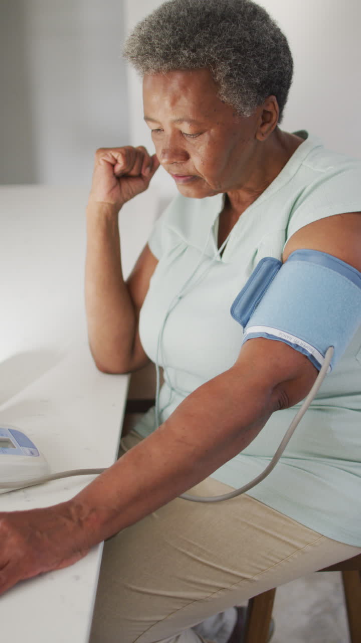 video vertical de una anciana afroamericana midiendo la presión en casa