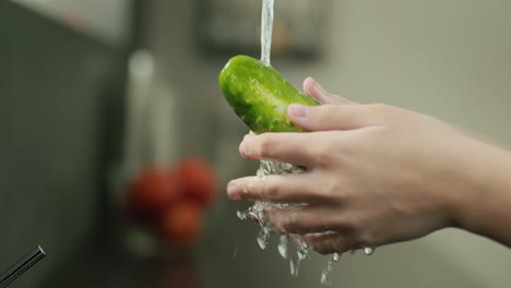 el pepino jugoso se lava bajo el agua del grifo de la cocina. vídeo en 4k en cámara lenta