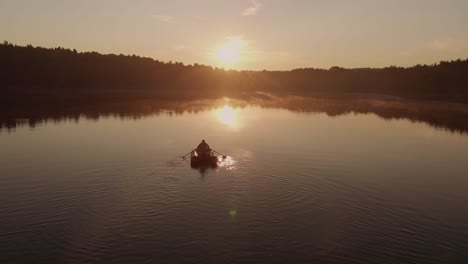 Hombre-Remando-En-Un-Bote-En-Un-Lago-Tranquilo-Rodeado-De-Abundantes-árboles-Durante-La-Puesta-De-Sol-En-Polonia