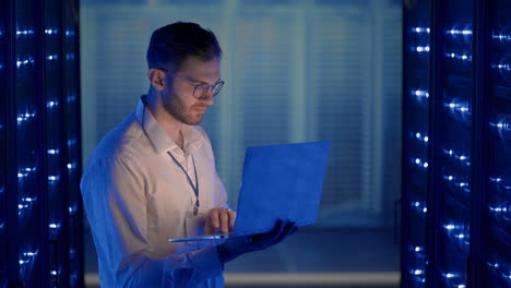 data center it specialists coworking in secure server room of cyberspace. male administrator pointing at error server cabinet running diagnostics on laptop computer