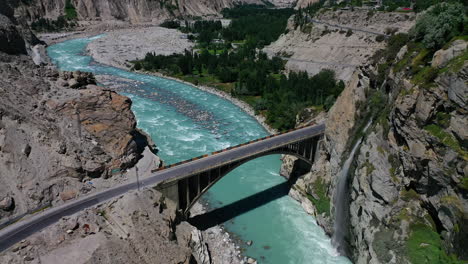 gorgeous aerial drone view of a waterfall and the ganish bridge over the hunza river in the mountains of pakistan