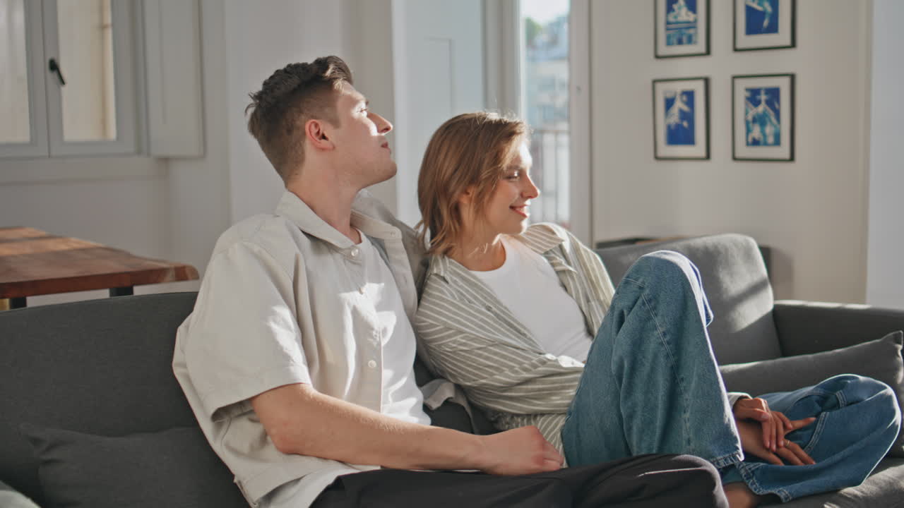 Home couple sharing conversation in sunlight. Closeup partners cuddling on sofa