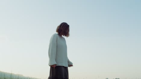 woman walking in a field at sunrise/sunset