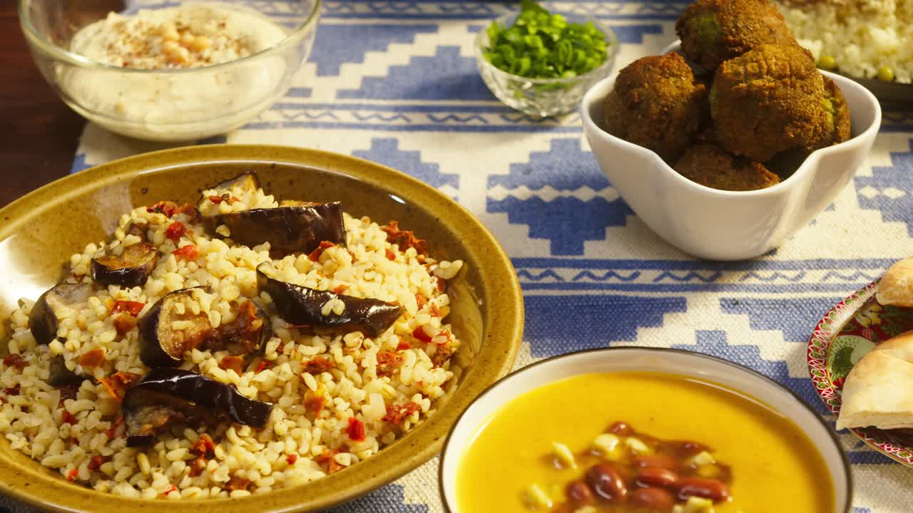 cocina árabe. bulgur con berenjena, falafel, sopa de frijoles en la mesa, comiendo pita con salsas. cultura tradicional de oriente medio. moutabal y ensalada de verduras en cuencos. delicioso arroz con carne