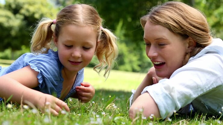 Madre felice sdraiata sull'erba con la sua bambina al parco
