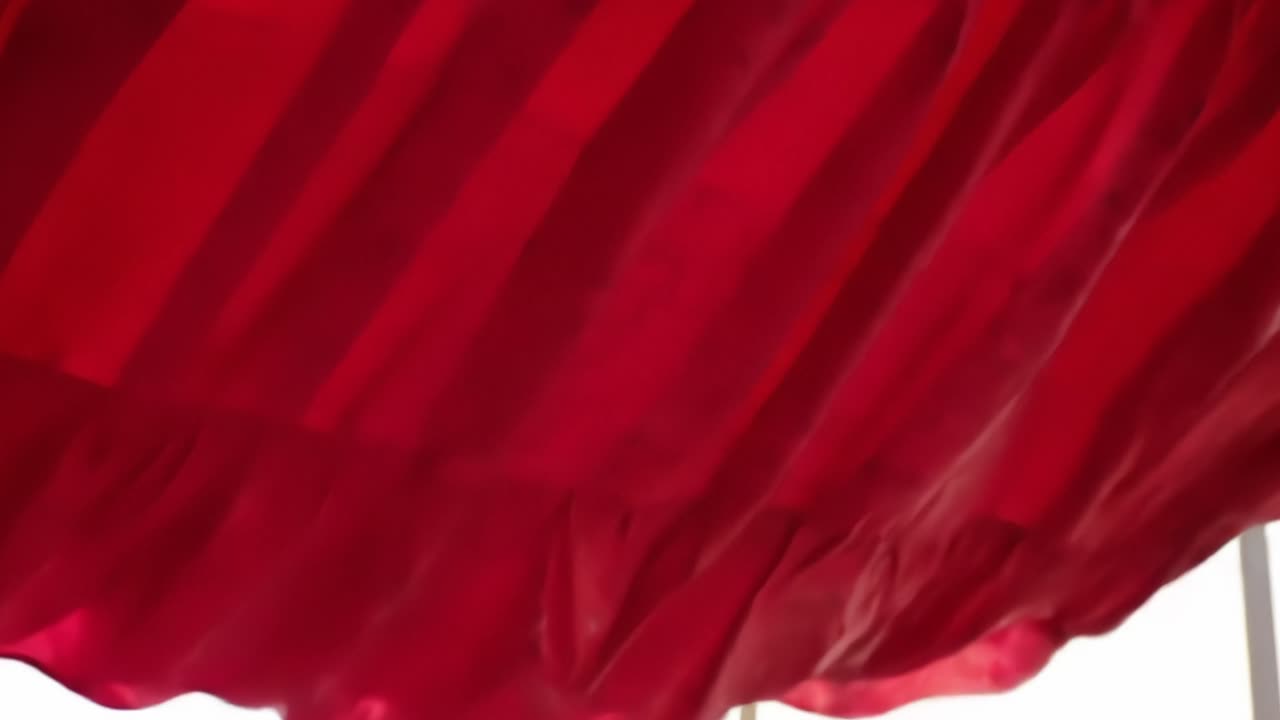A Captivating Dance of Crimson Fabric: Exploring the Graceful Movement and Texture of Flowing Red Drapery in Natural Light