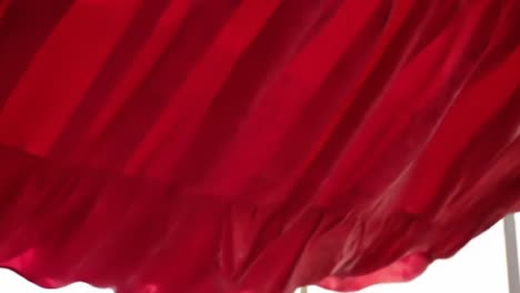 a captivating dance of crimson fabric: exploring the graceful movement and texture of flowing red drapery in natural light