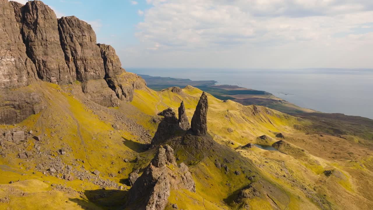 Aerial drone footage of the dramatic mountain landscapes and Old man of Storr on the Isle of Skye, Scotland. Sweeping panoramic views of majestic peaks, green valleys, and wild nature
