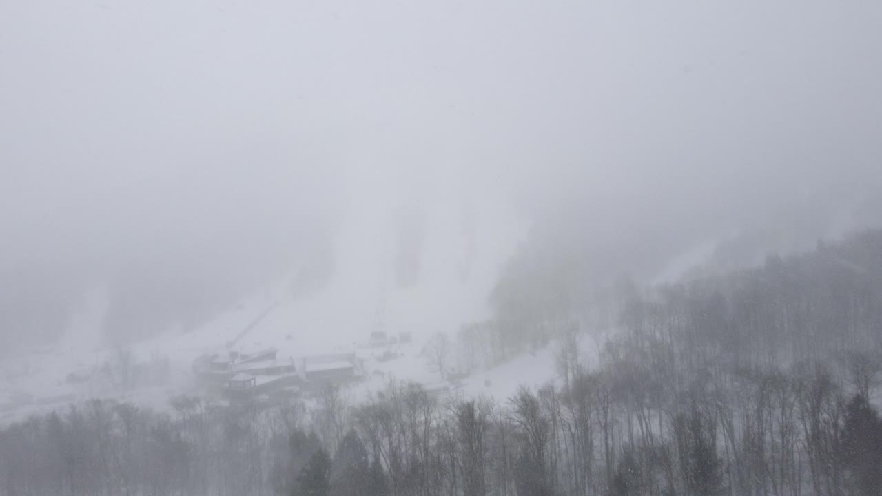 Snowy mountain landscape covered in thick fog with faint ski slope visible, Orford, Quebec, Canada.