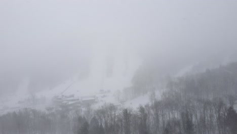 snowy mountain landscape covered in thick fog with faint ski slope visible, orford, quebec, canada.