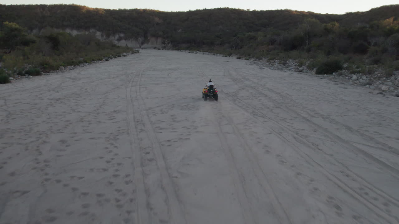 Ripresa drone che segue un uomo in moto su un terreno polveroso