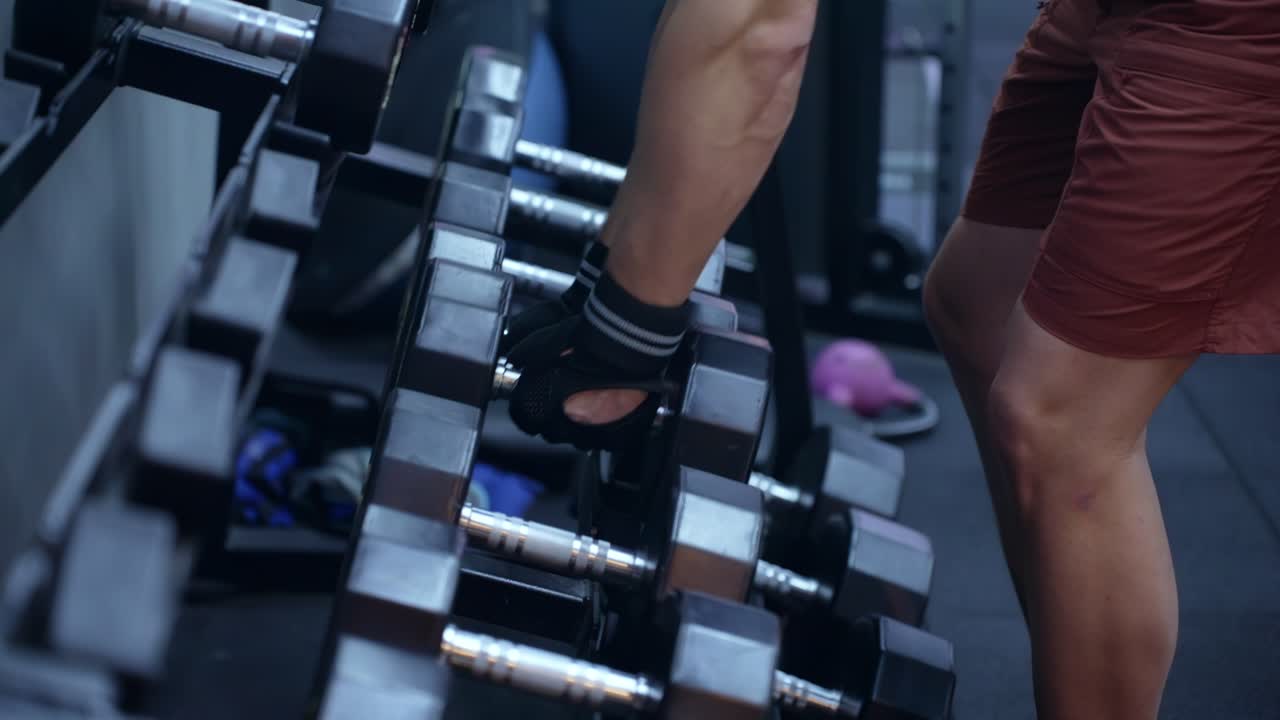 Man picking dumbbells at the gym - closeup