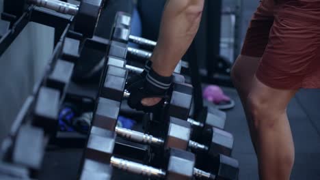 man picking dumbbells at the gym - closeup