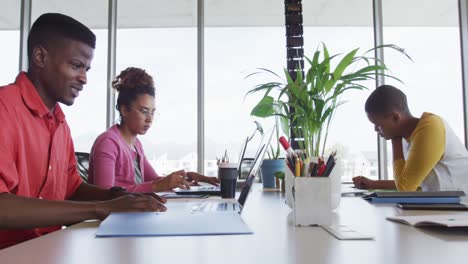 african american creative businessman celebrating in office, with diverse female colleagues working