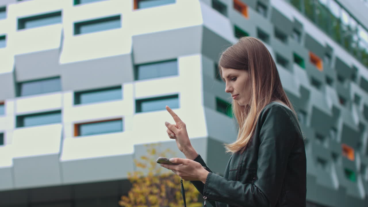 Woman using smartphone outside modern building