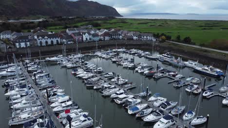 Scenic-luxurious-waterfront-harbour-apartment-village-yachts-and-sailboats-under-mountain-coastline-aerial-orbiting-right-view