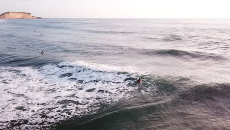 superficie de agua del océano esmeralda con surfistas flotando en la playa de olón en ecuador