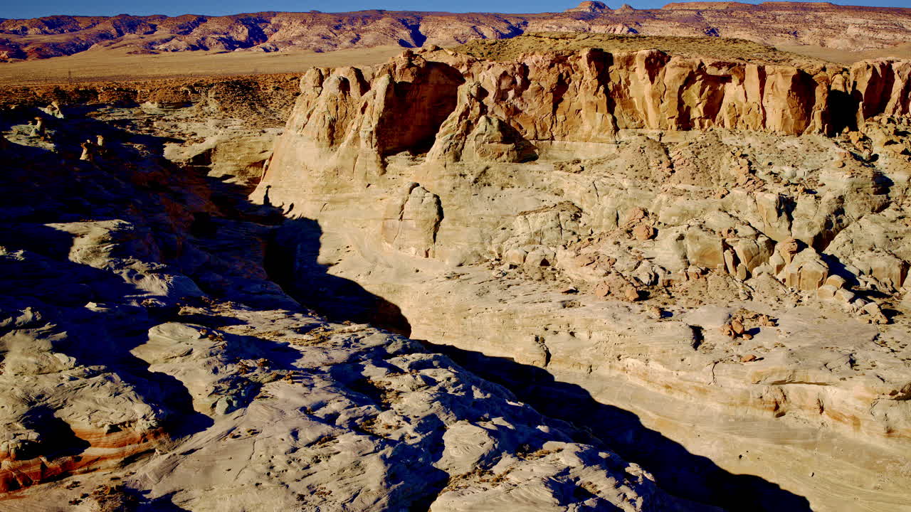 Aerial view sweeping over wave-like red rocks near Page, Arizona.