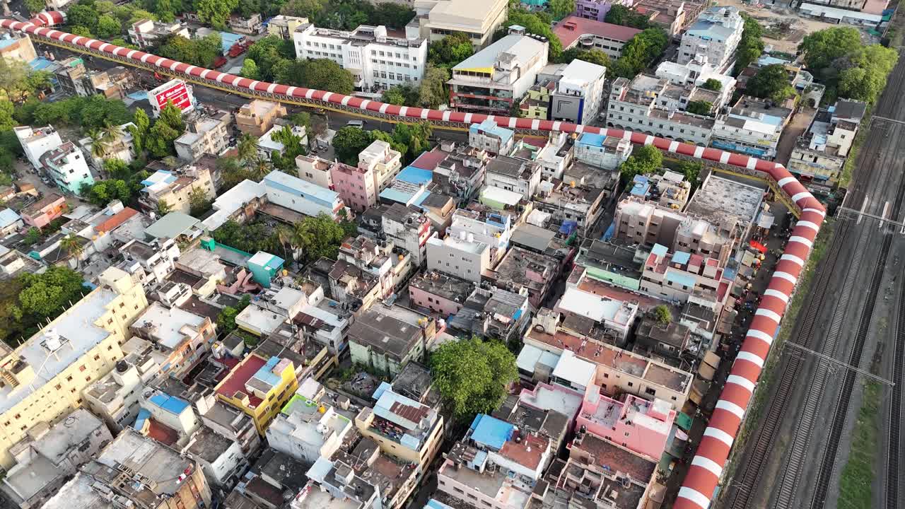 Aerial view of the neighborhood. A long, winding pedestrian walkway with a red and white striped roof is the central feature, snaking through a densely packed area of low-rise buildings