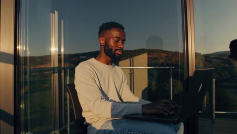 man working on laptop on balcony