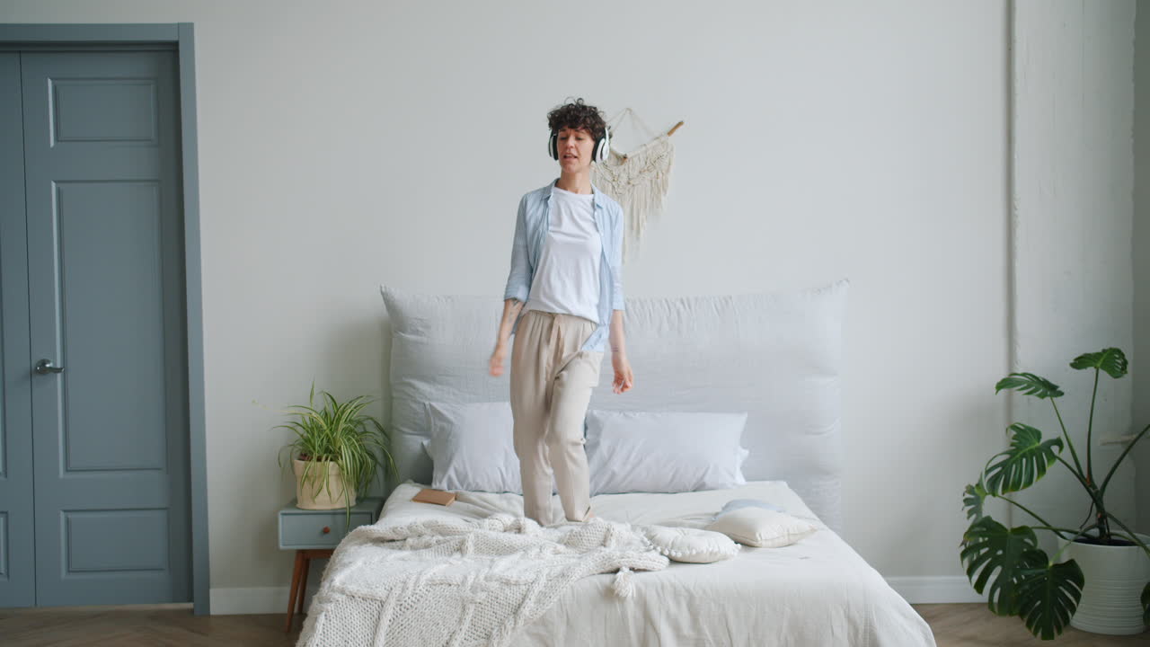 Woman Dancing on a Bed While Listening to Music
