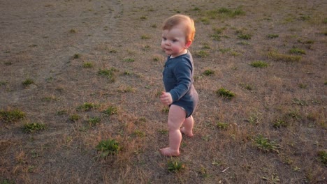 happy sitting toddler quickly stands up at beach and takes first steps forward