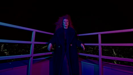 mujer con un abrigo oscuro en un techo por la noche