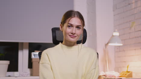 Retrato-De-Una-Hermosa-Joven-Sentada-En-Una-Silla-De-Oficina-Y-Sonriendo-A-La-Cámara