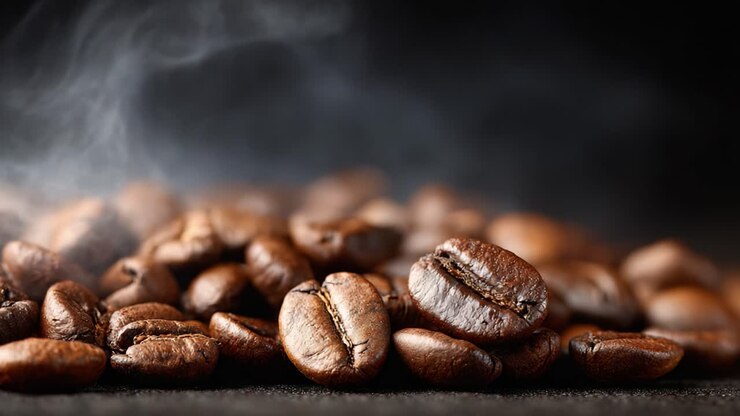 Aromatische Kaffeebohnen im Fokus: Kräftige, dunkel geröstete Kaffeebohnen verströmen ihr duftendes Aroma mit Dampfschwaden in einer mokkafarbenen Umgebung.
