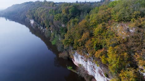 Fpv-drohne,-Die-Im-Herbst-Entlang-Einer-Klippe-über-Einem-Fluss-Mit-Bäumen-Fliegt,-Fluss-Dordogne---Bac-De-Sors-In-Frankreich