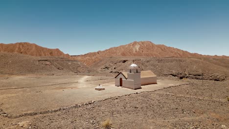 behold the captivating charm of a secluded oasis in atacama's rugged terrain as a small church in a lush valley is captured in awe-inspiring drone footage that showcases its natural beauty from above