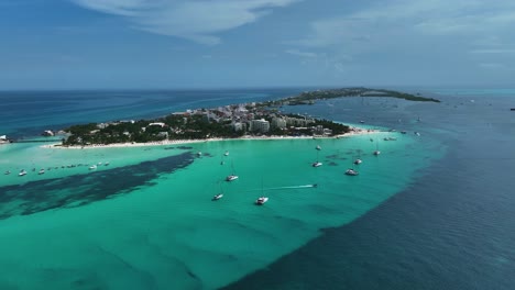 Vista-Aérea-Hacia-Un-Barco,-Conduciendo-En-Medio-De-Veleros-En-Isla-Mujeres,-México