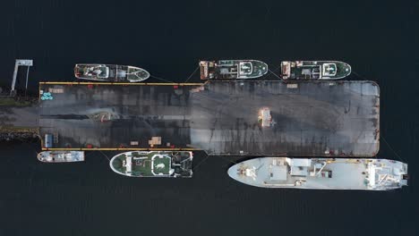 fishing boats anchored at concrete dock in harbor, top down