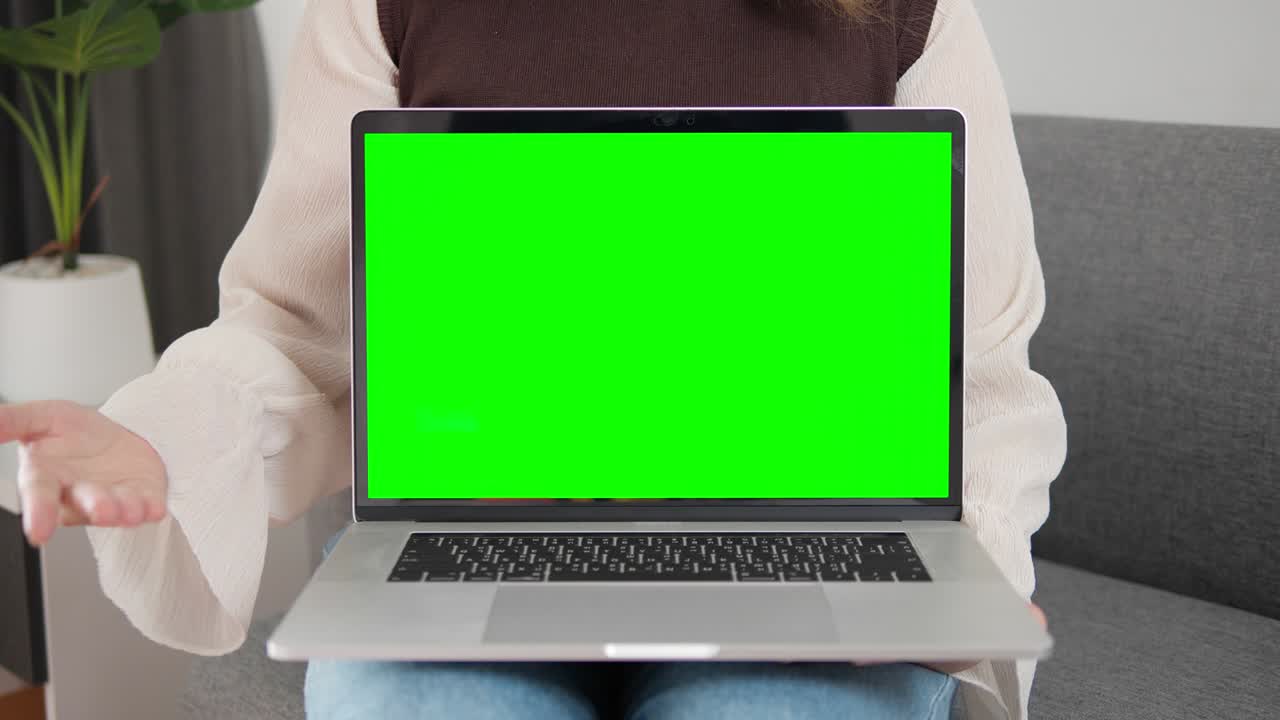 Woman presentation laptop with green screen on sofa at home