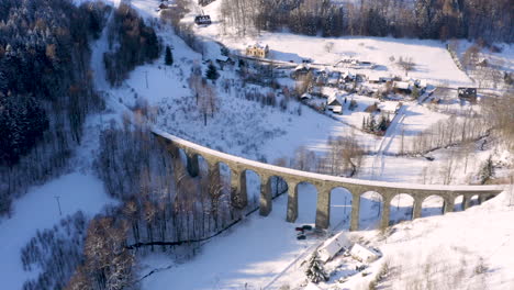 stone train viaduct railroad around a small village in winter snow