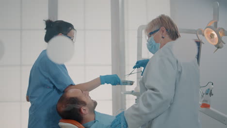 stomatologist and nurse doing extraction procedure on patient