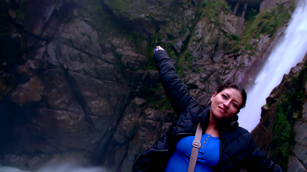 Happy woman in blue sweater in front of waterfall Devil's Cauldron