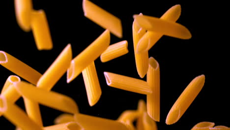 Penne-bouncing-against-black-background