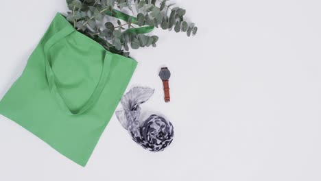 video of green canvas bag with plant, scarf, watch, copy space on on white background