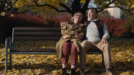 Caucasian-senior-couple-sitting-at-the-bench-at-park-and-embracing