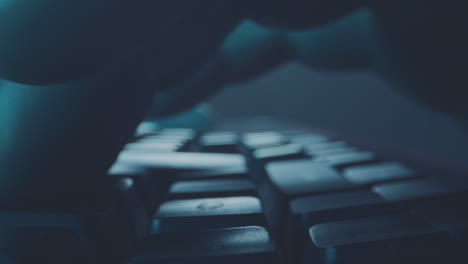 un primer plano de manos escribiendo en un teclado por la noche.