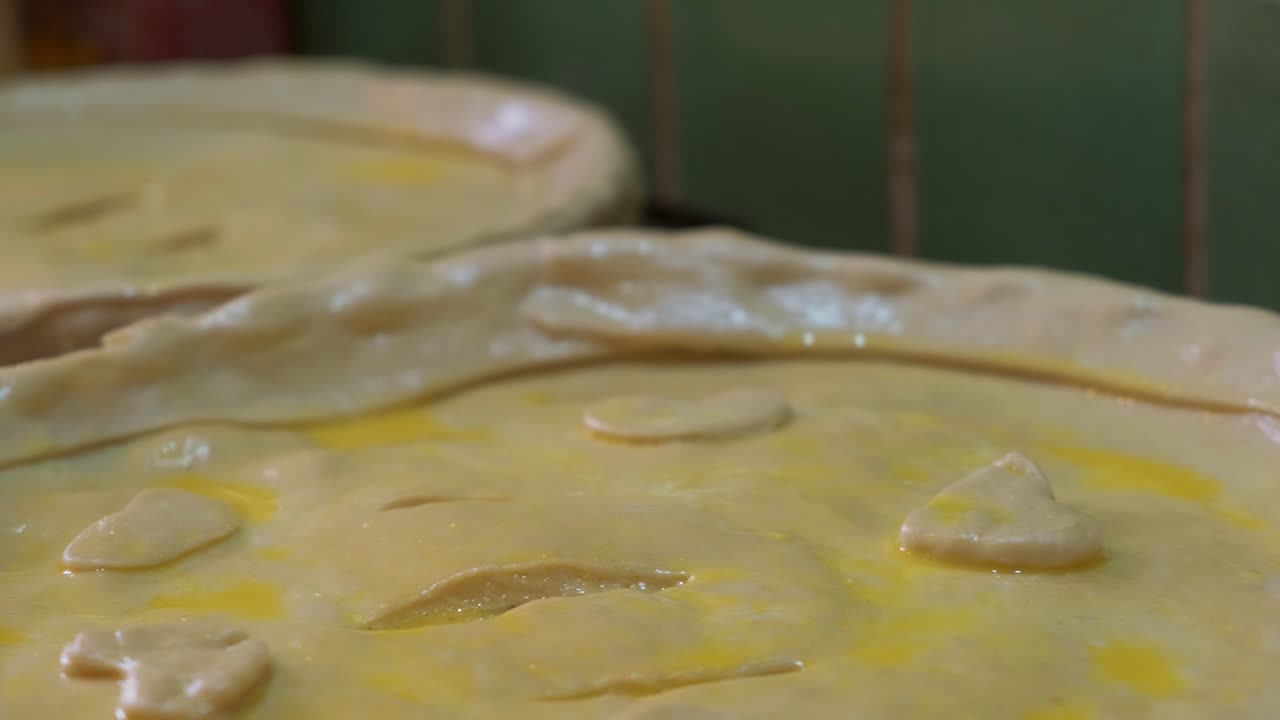 Close up of two trays filled with unbaked homemade pies, neatly shaped and ready for the oven.