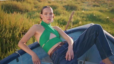 mujer atractiva posando barco a la luz del sol. modelo elegante y sexy descanso campo verde